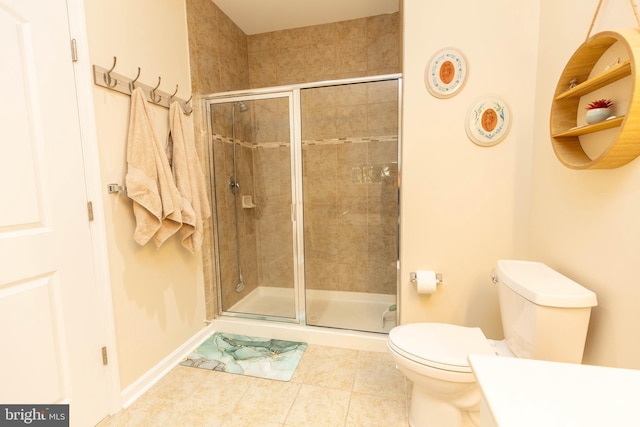 bathroom featuring tile patterned flooring, toilet, and a shower with shower door