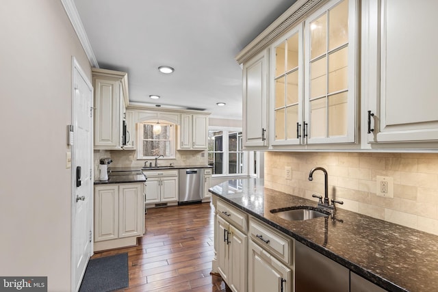 kitchen with dark hardwood / wood-style flooring, ornamental molding, stainless steel appliances, sink, and dark stone countertops