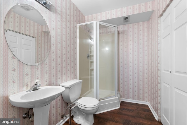 bathroom featuring hardwood / wood-style floors, toilet, and a shower with shower door