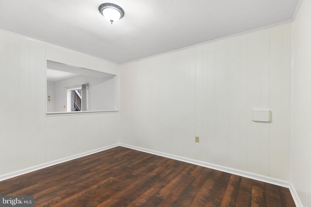 spare room featuring dark hardwood / wood-style floors, crown molding, and wood walls