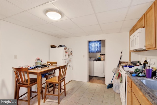 tiled dining area with washer and clothes dryer, a drop ceiling, and sink