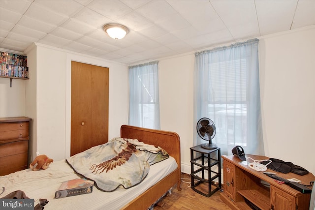 bedroom featuring light hardwood / wood-style floors, multiple windows, and crown molding