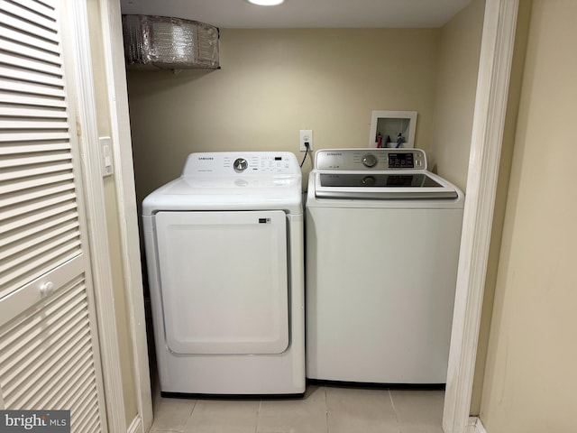 clothes washing area with washing machine and dryer and light tile patterned floors