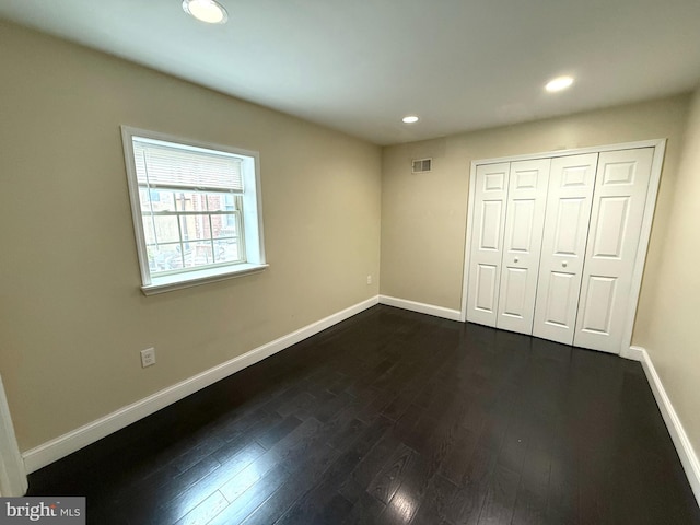 unfurnished bedroom with a closet and dark hardwood / wood-style floors