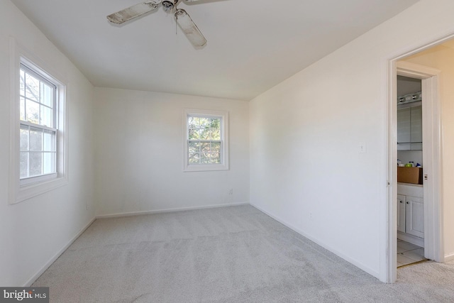 carpeted spare room featuring ceiling fan and a healthy amount of sunlight