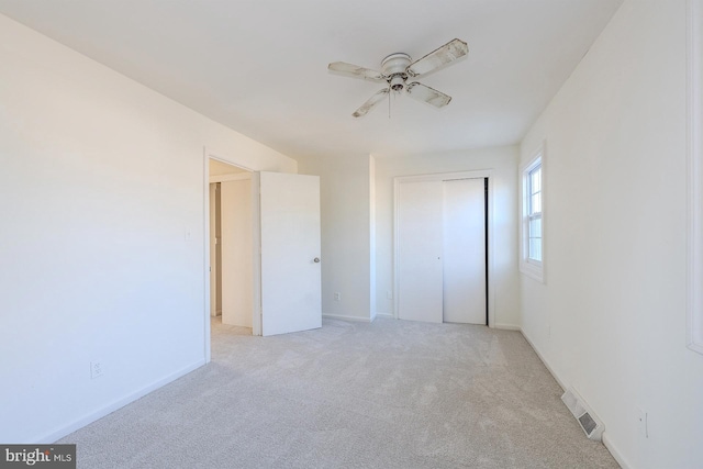 unfurnished bedroom featuring ceiling fan, a closet, and light colored carpet