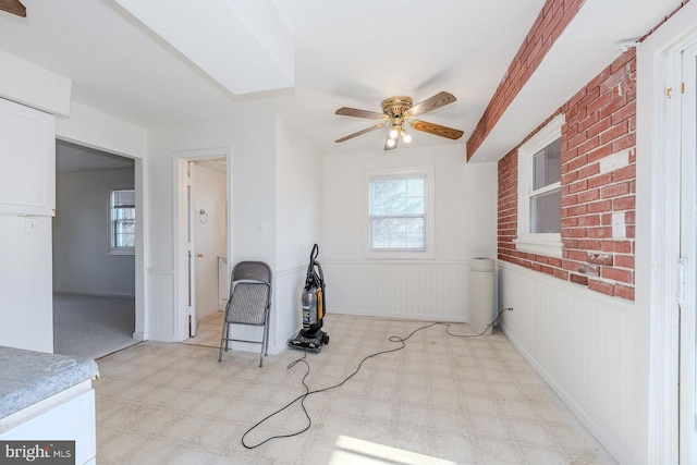 interior space with ceiling fan and wooden walls