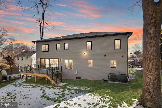 snow covered property featuring central AC, a deck, and a lawn