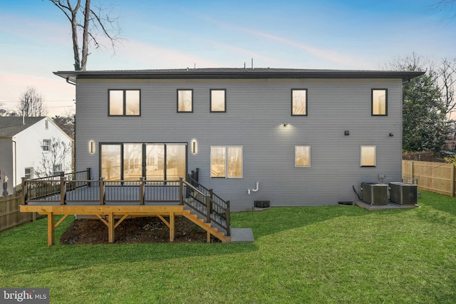 back house at dusk featuring a yard, a wooden deck, and cooling unit