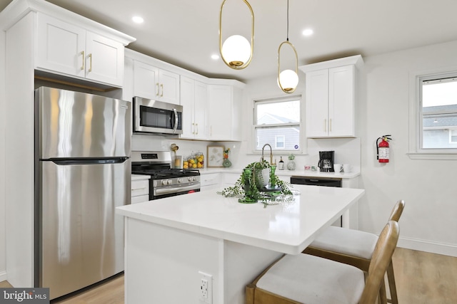 kitchen with pendant lighting, plenty of natural light, white cabinets, and stainless steel appliances