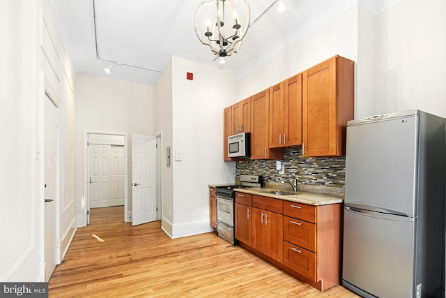 kitchen featuring backsplash, a notable chandelier, light wood-type flooring, and stainless steel appliances