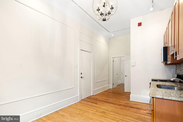 hall featuring light hardwood / wood-style floors, track lighting, a notable chandelier, and sink