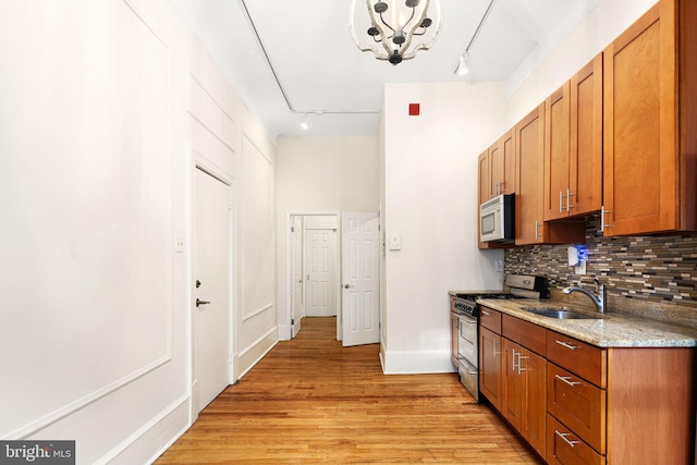 kitchen featuring sink, backsplash, track lighting, appliances with stainless steel finishes, and light wood-type flooring