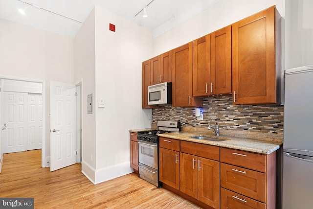 kitchen with sink, rail lighting, light hardwood / wood-style flooring, refrigerator, and stainless steel range with gas stovetop