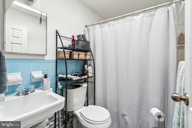 bathroom featuring toilet, sink, and tile walls