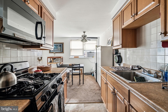 kitchen with decorative backsplash, ceiling fan, sink, black gas range, and light tile patterned flooring