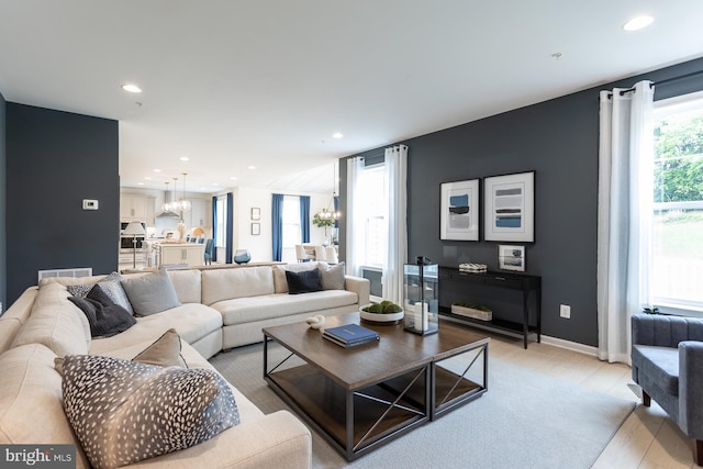 living room featuring a chandelier, plenty of natural light, and light hardwood / wood-style floors