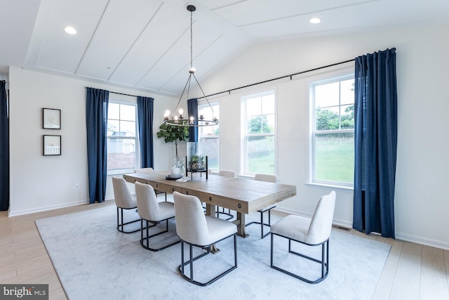 dining area featuring lofted ceiling, light wood-type flooring, and an inviting chandelier