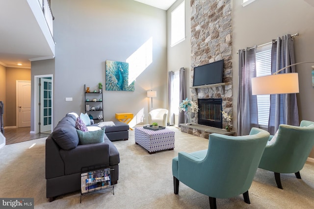 living room featuring carpet flooring, crown molding, a fireplace, and a towering ceiling