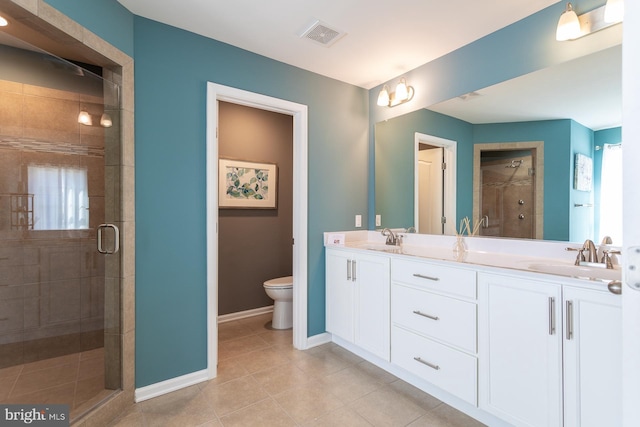 bathroom featuring tile patterned flooring, vanity, a shower with shower door, and toilet