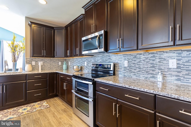 kitchen with decorative backsplash, appliances with stainless steel finishes, dark brown cabinetry, and light stone countertops