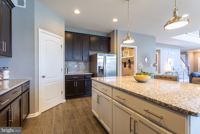 kitchen featuring backsplash, dark brown cabinets, decorative light fixtures, stainless steel fridge with ice dispenser, and a center island