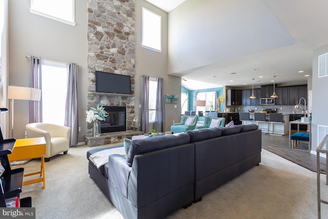 living room featuring plenty of natural light, light colored carpet, a towering ceiling, and a fireplace