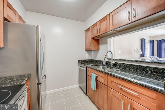 kitchen featuring dark stone countertops, sink, light tile patterned floors, and appliances with stainless steel finishes