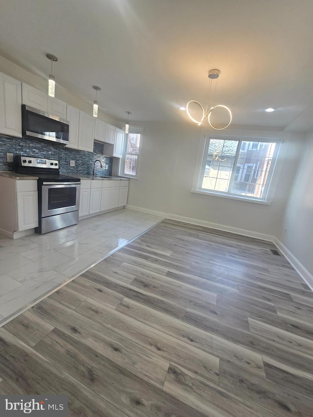 kitchen with white cabinets, decorative light fixtures, and appliances with stainless steel finishes