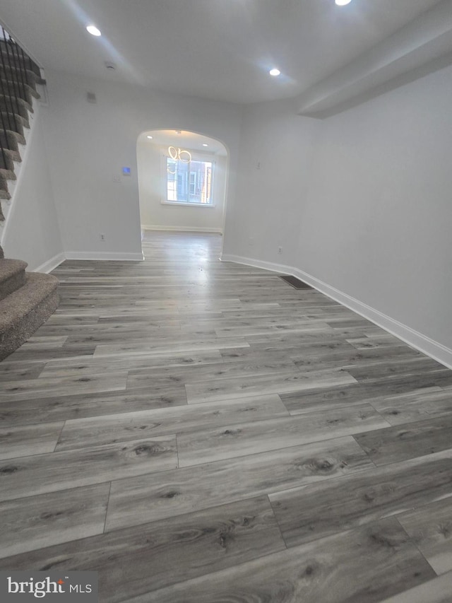 unfurnished room with wood-type flooring and an inviting chandelier