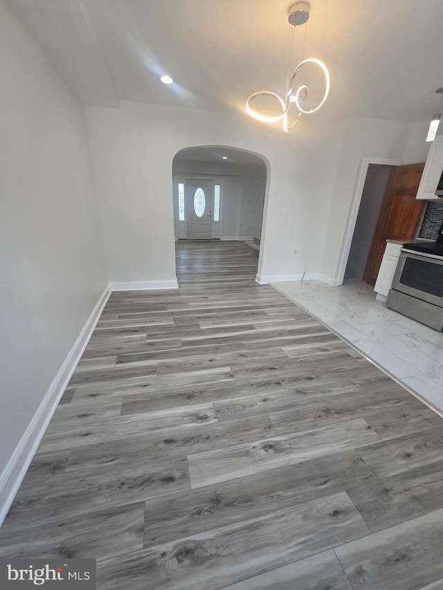 unfurnished living room featuring wood-type flooring and an inviting chandelier