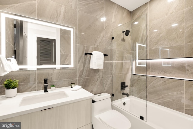 full bathroom featuring vanity, enclosed tub / shower combo, tile walls, and toilet