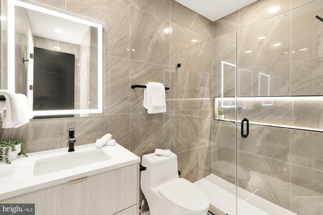 bathroom featuring walk in shower, vanity, tile walls, and toilet