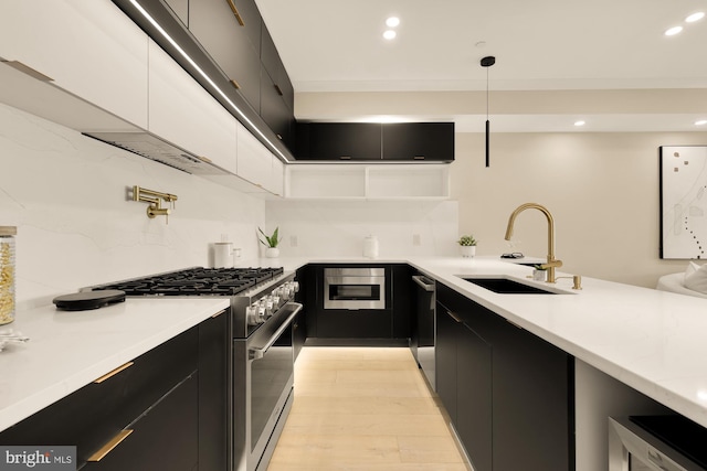 kitchen with sink, stainless steel appliances, tasteful backsplash, decorative light fixtures, and light wood-type flooring