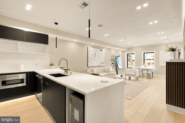 kitchen featuring kitchen peninsula, beverage cooler, sink, oven, and hanging light fixtures