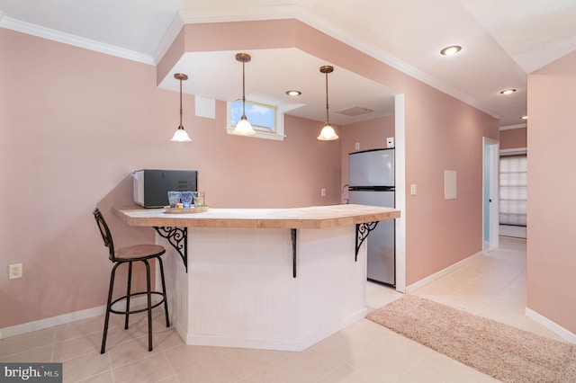 kitchen with pendant lighting, refrigerator, kitchen peninsula, and a breakfast bar area