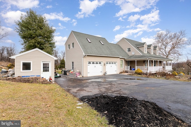 view of side of home featuring a porch, a lawn, and a garage