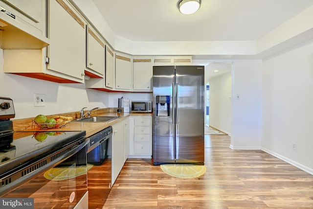 kitchen featuring sink, range hood, light hardwood / wood-style flooring, and black appliances