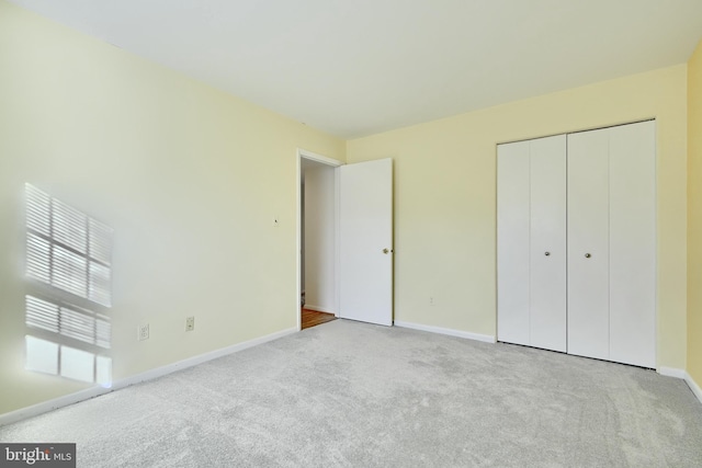 unfurnished bedroom with a closet and light colored carpet