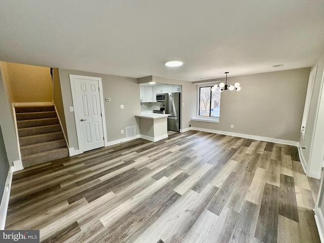 unfurnished living room featuring hardwood / wood-style flooring and an inviting chandelier