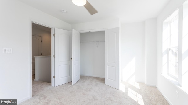 unfurnished bedroom with ceiling fan, a closet, light carpet, and multiple windows