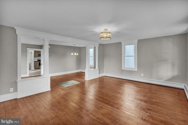 unfurnished living room featuring wood-type flooring, a baseboard heating unit, and a notable chandelier