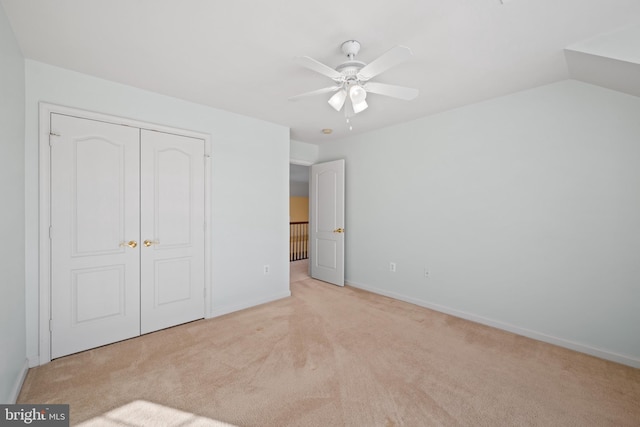 unfurnished bedroom featuring ceiling fan, a closet, light colored carpet, and lofted ceiling