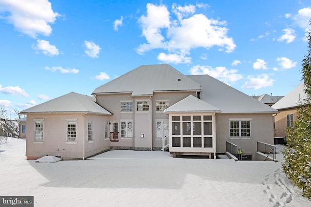 snow covered house featuring a sunroom and central air condition unit