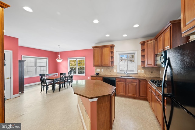 kitchen with a center island, black appliances, sink, hanging light fixtures, and tasteful backsplash