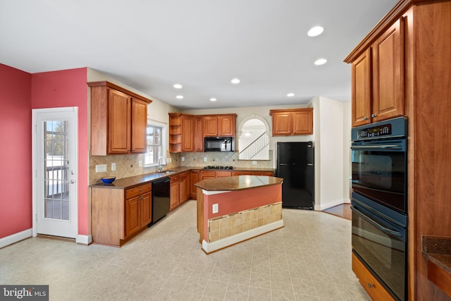 kitchen featuring tasteful backsplash, a center island, black appliances, and sink