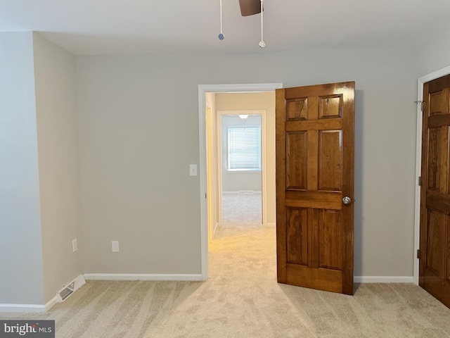 empty room featuring ceiling fan and light colored carpet