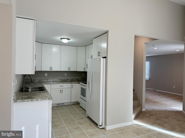 kitchen with stone counters, sink, light colored carpet, white appliances, and white cabinets