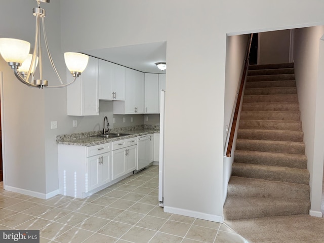 kitchen with sink, light tile patterned floors, a notable chandelier, dishwasher, and white cabinetry