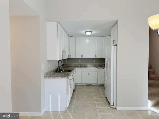 kitchen featuring sink, light tile patterned floors, white refrigerator, stone countertops, and white cabinetry